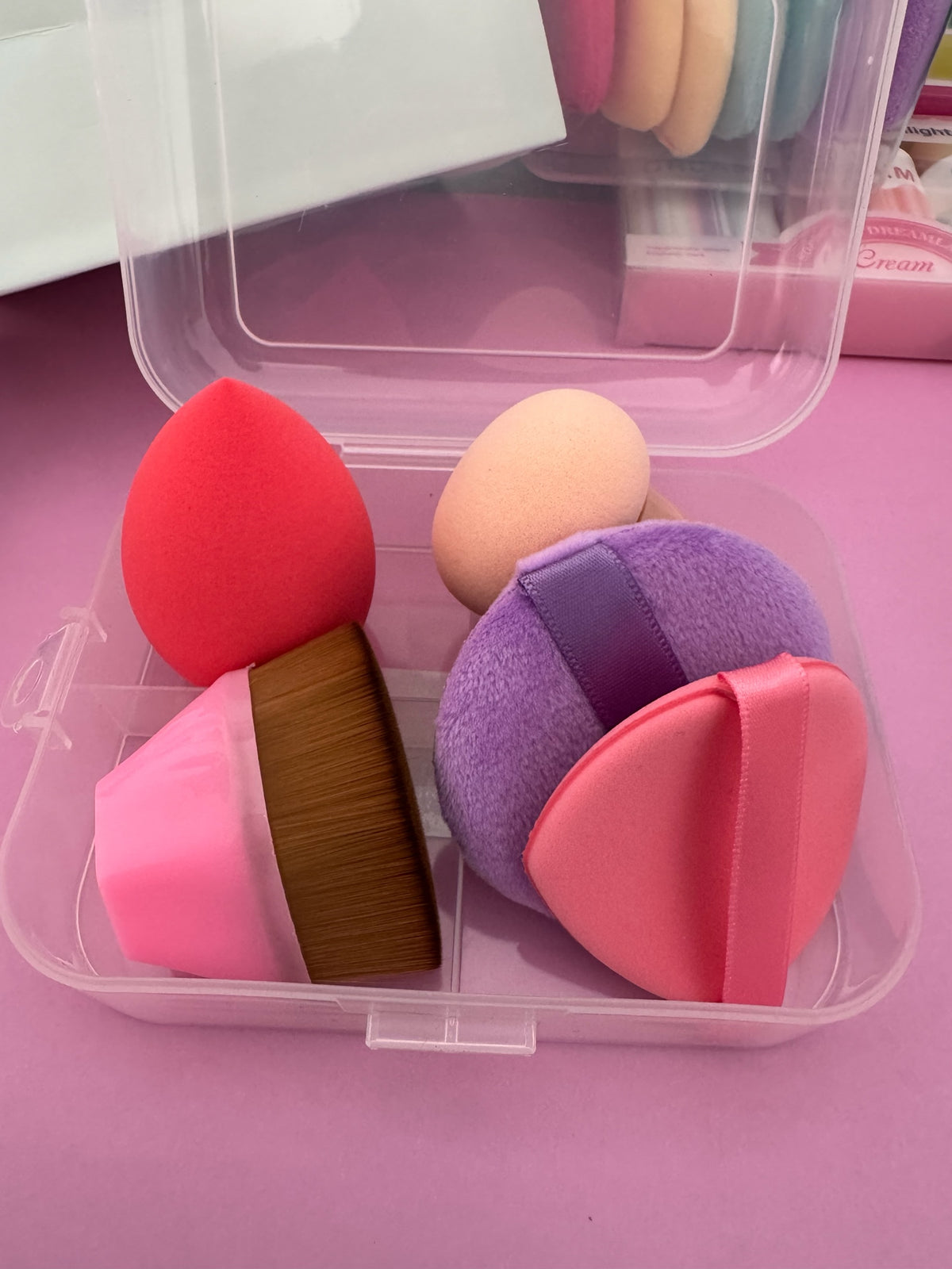 Set de maquillaje Brena con esponjas coloridas, borlas suaves y brocha de base en un estuche organizador transparente.