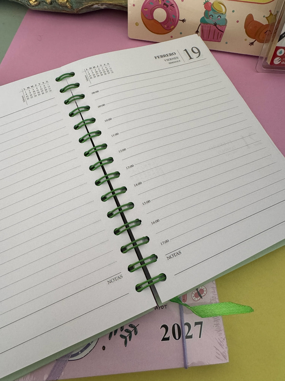 Agenda semanal Brena 2027 con espiral verde, vista de página diaria con franjas horarias y sección de notas