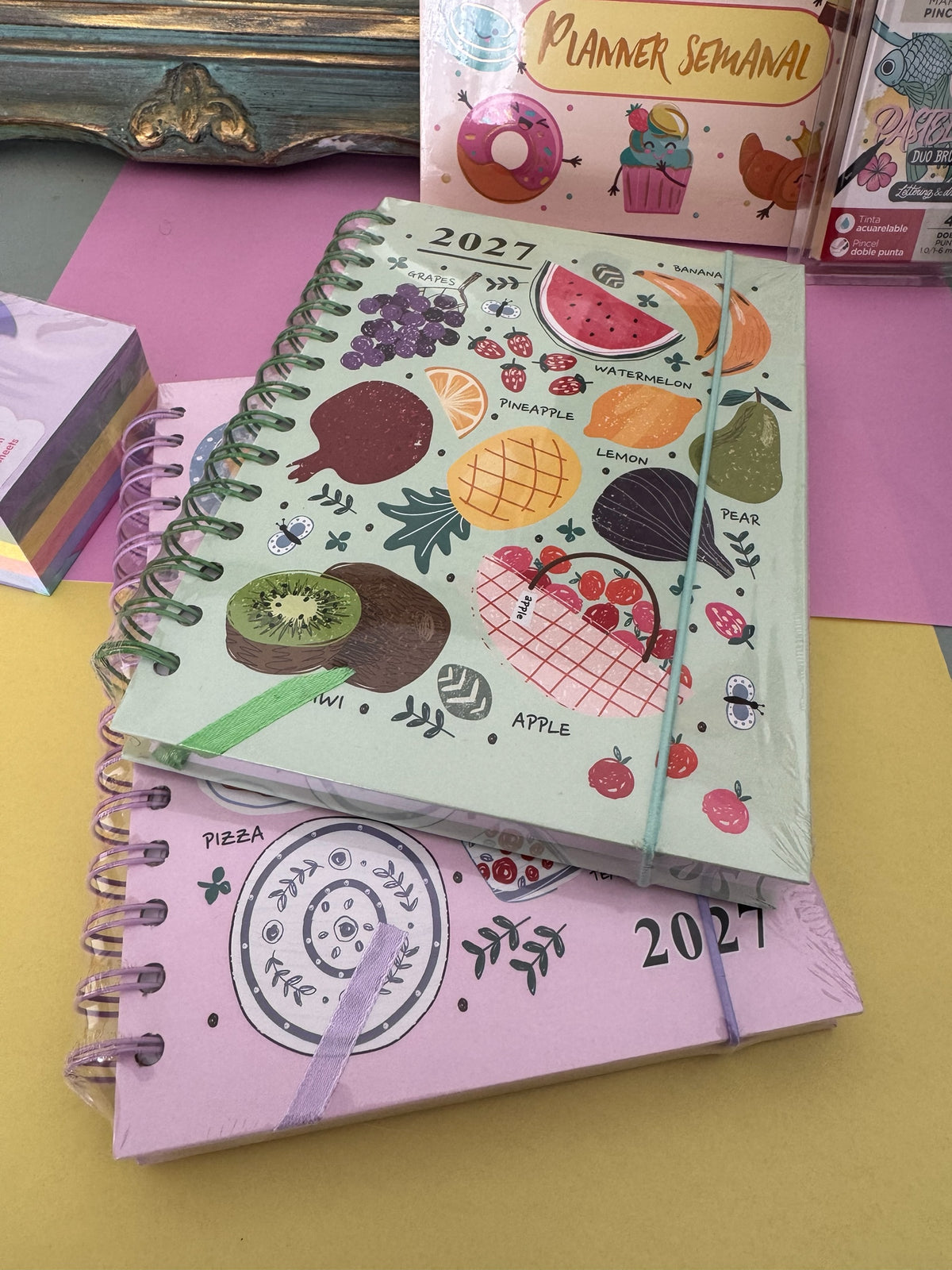 Agenda semanal Brena 2027 con diseño de frutas coloridas sobre fondo verde y cierre elástico, encuadernación en espiral