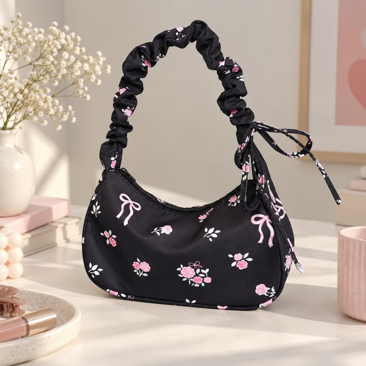 Bolso de hombro Brena negro con estampado de rosas y lazos, con asa fruncida tipo scrunchie y estilo coquette.
