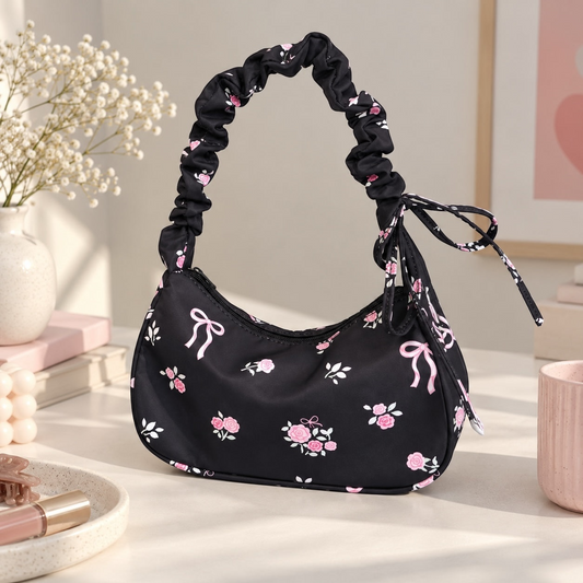 Bolso de hombro Brena negro con estampado de rosas y lazos, con asa fruncida tipo scrunchie y estilo coquette.