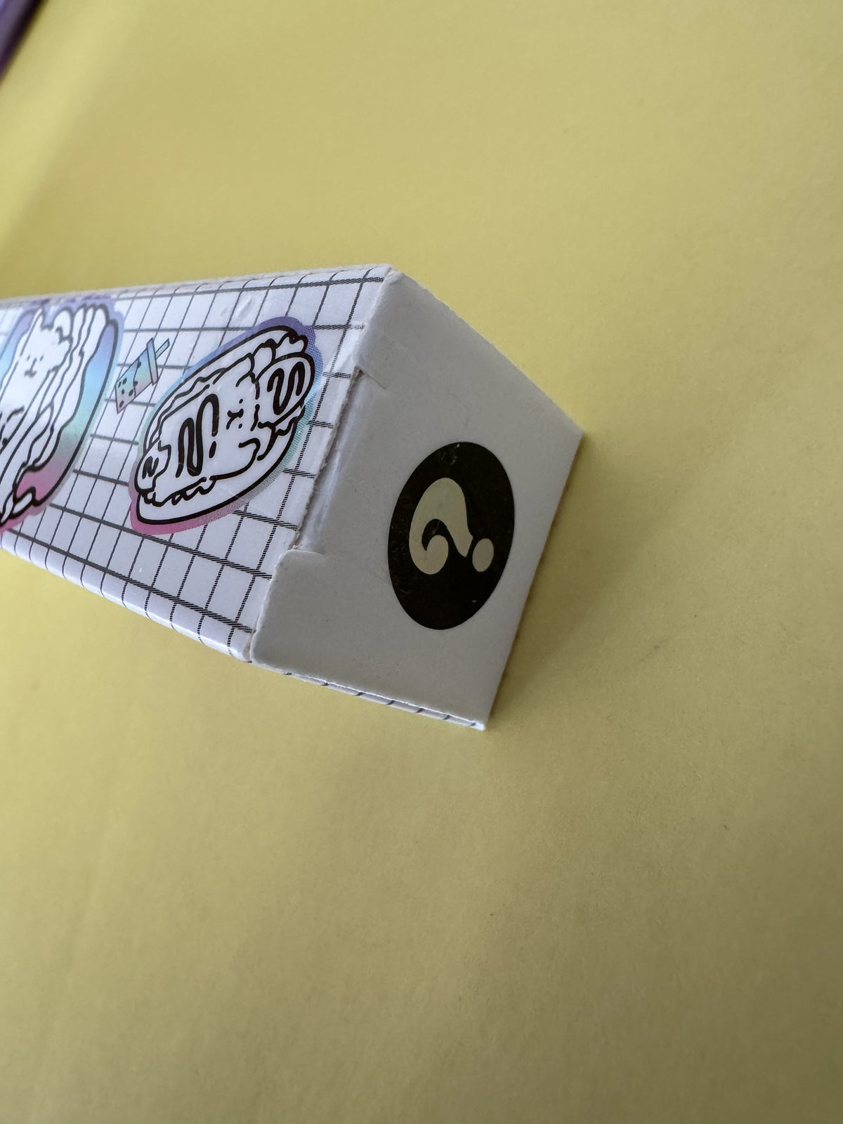 Caja sorpresa Brena con diseño cuadriculado y pegatinas de cachorros kawaii sobre fondo amarillo