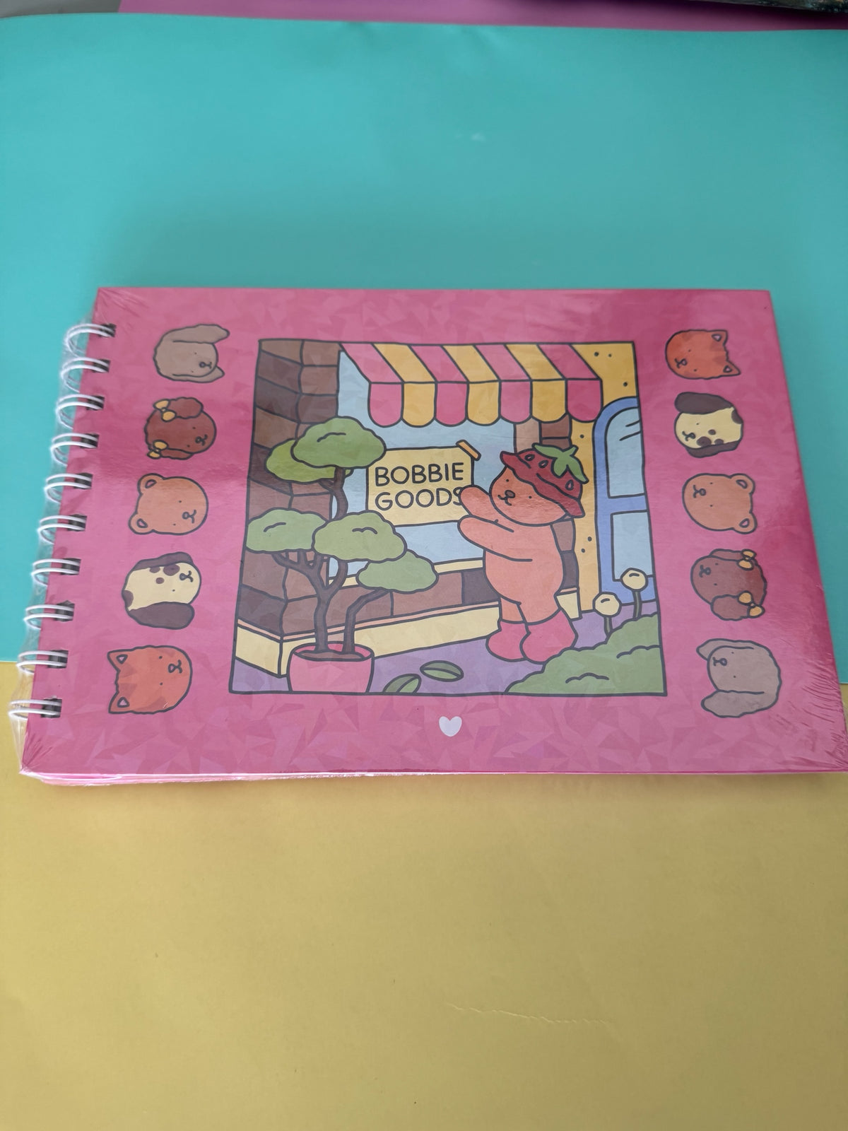 Cuaderno de notas Brena con encuadernación en espiral, diseño horizontal kawaii de osito Bobbie Goods en color rosa.