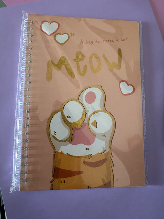 Cuaderno Brena con espiral, portada color melocotón con ilustración de patita de gato y frase A day to raise a cat.