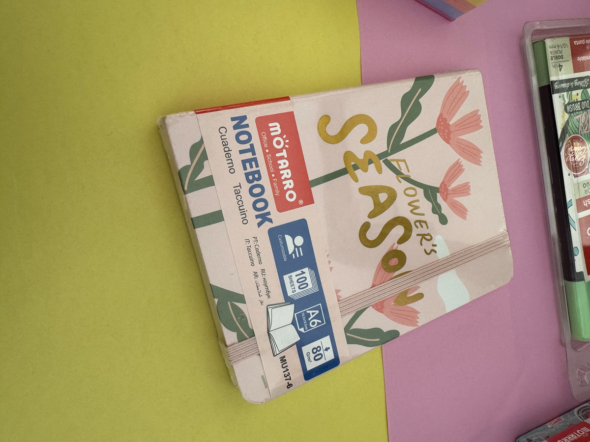 Cuaderno A6 Brena con diseño floral, tapa beige, banda elástica y 100 hojas de papel de alta calidad.