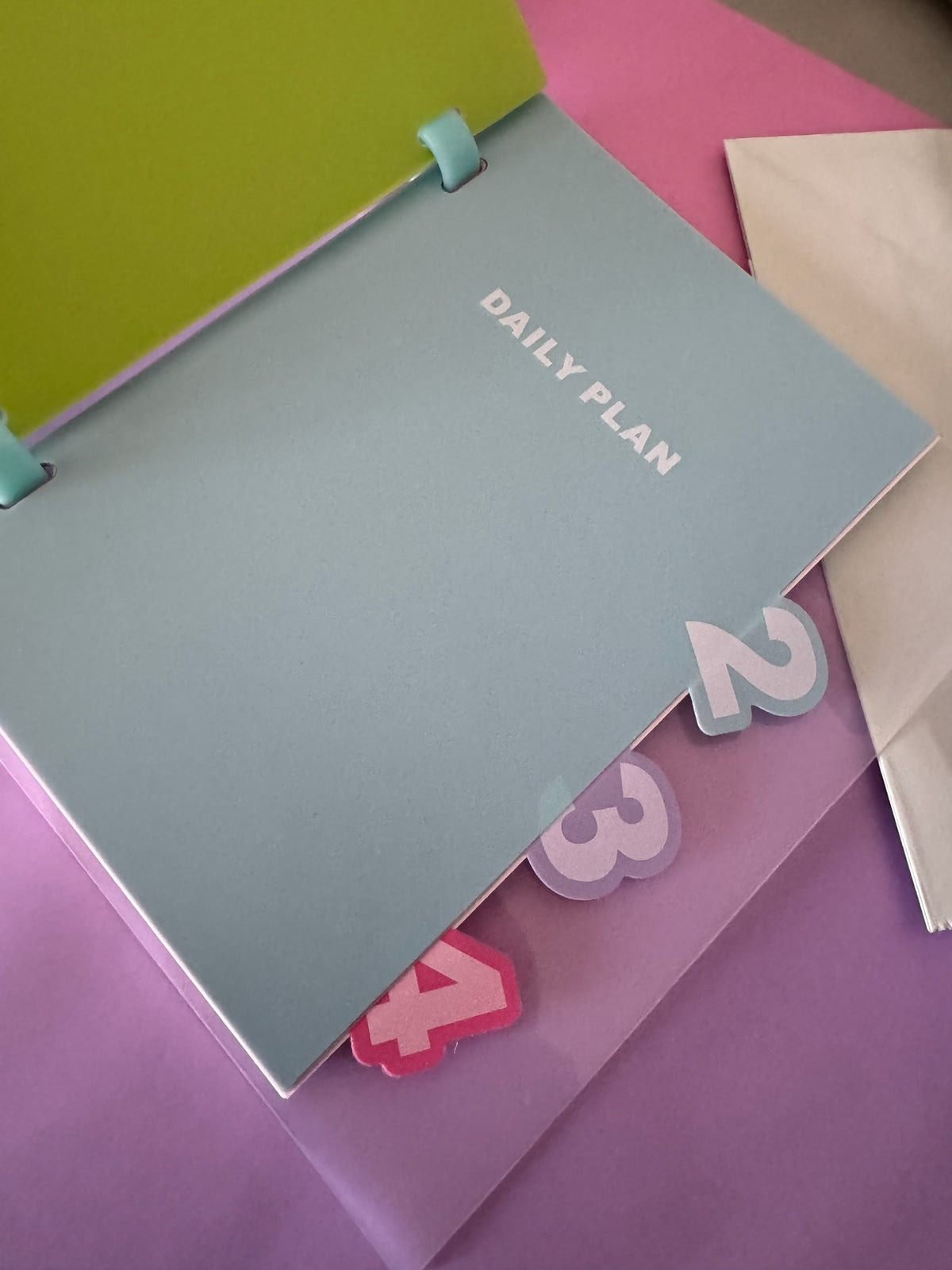 Cuaderno de notas Brena con hojas intercambiables, separadores numerados coloridos y portada azul con texto Daily Plan.