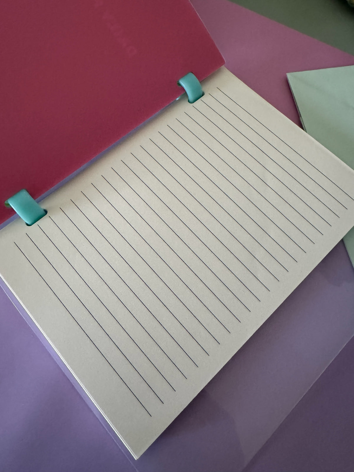 Cuaderno Brena de hojas rayadas intercambiables con encuadernación de anillas turquesa y portada fucsia