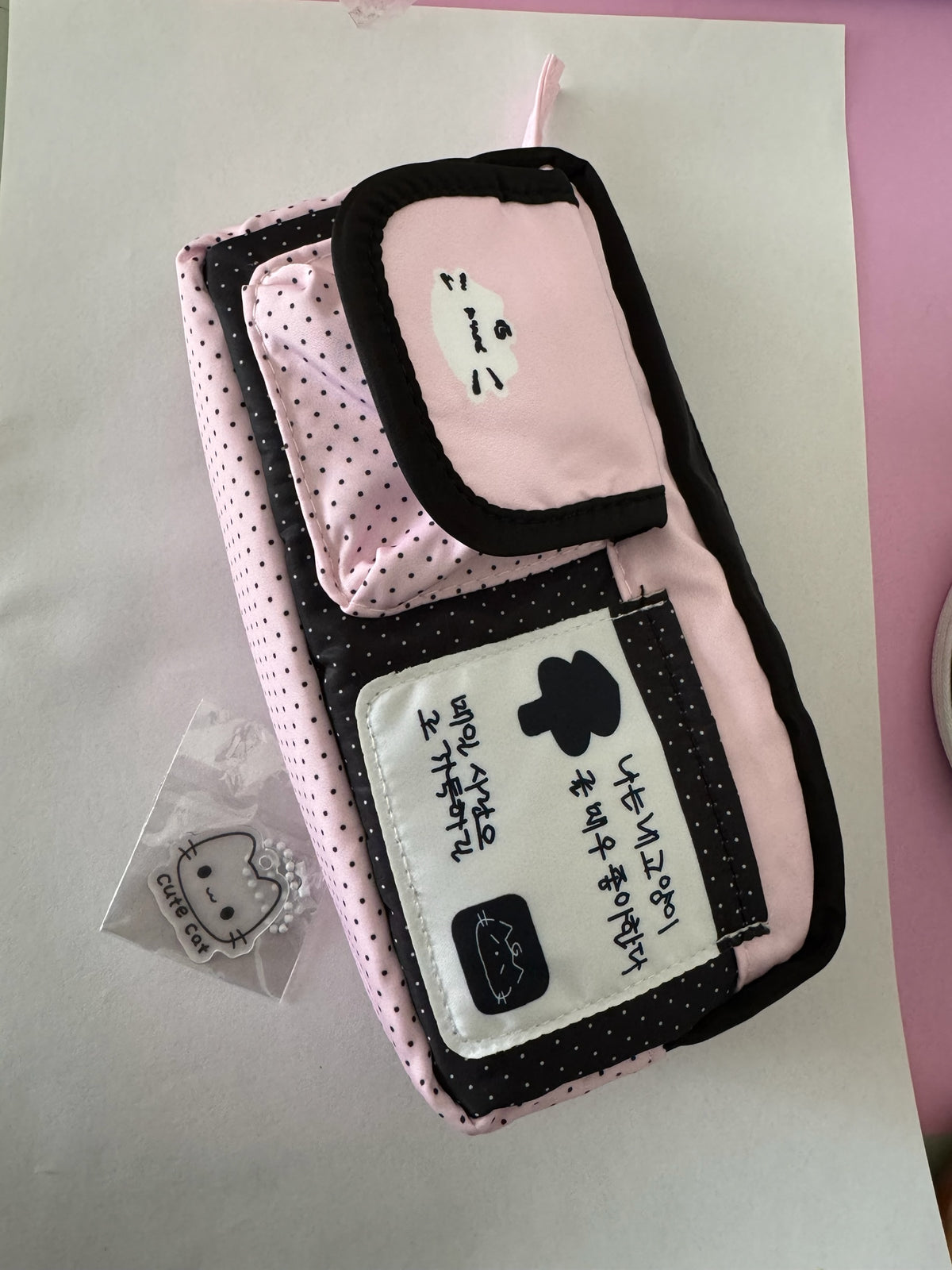 Estuche organizador escolar Brena rosa y negro con estampado de lunares, diseño de gato y llavero decorativo incluido.