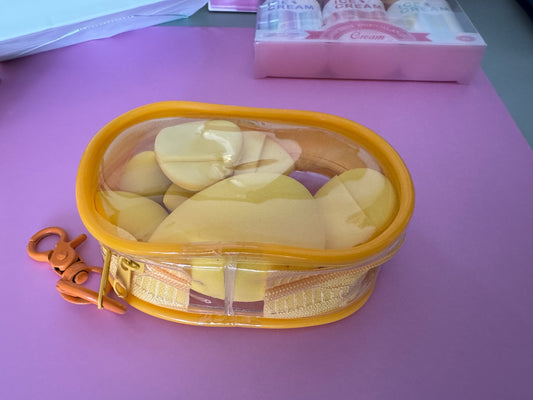 Estuche transparente Brena de color amarillo con esponjas de maquillaje suaves y flexibles y gancho tipo mosquetón.