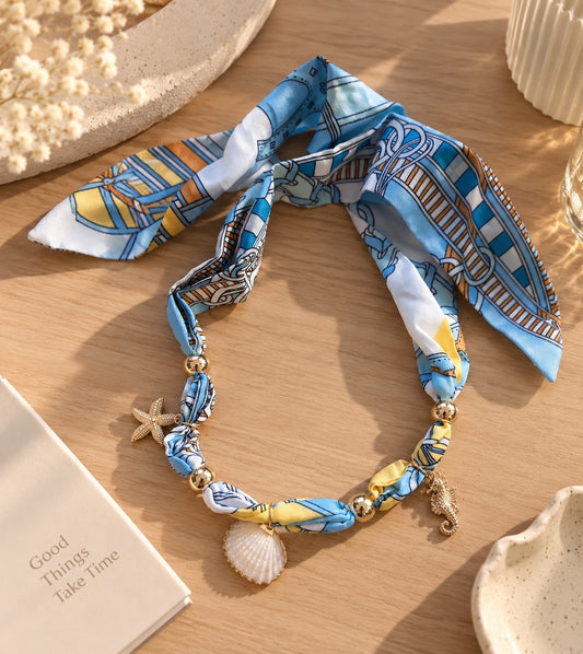 Gargantilla Brena de pañuelo en seda azul y amarillo con dijes de estrella de mar, caballito de mar y concha marina.