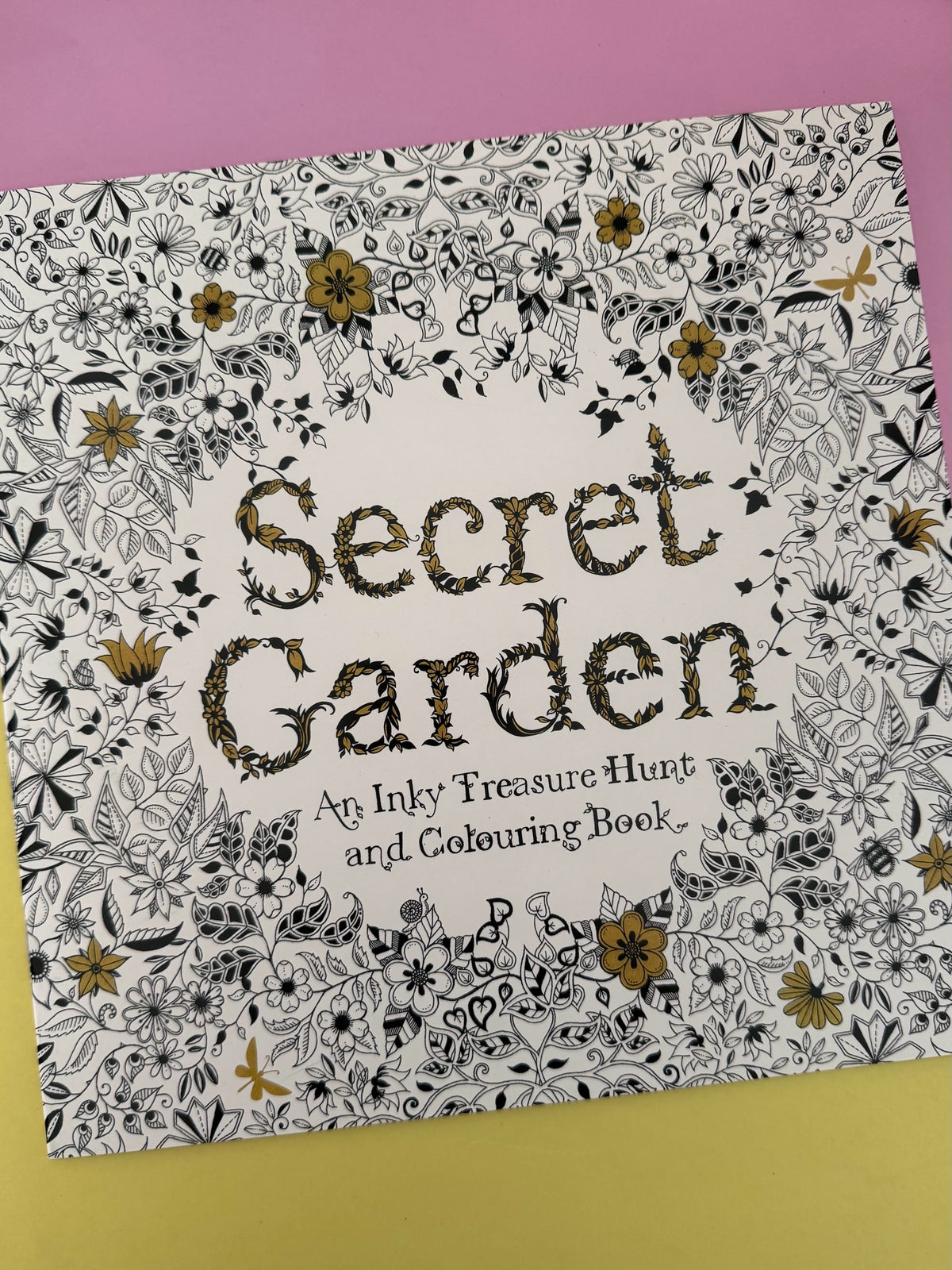 Libro de colorear Brena Secret Garden con ilustraciones botánicas detalladas en blanco, negro y toques dorados.