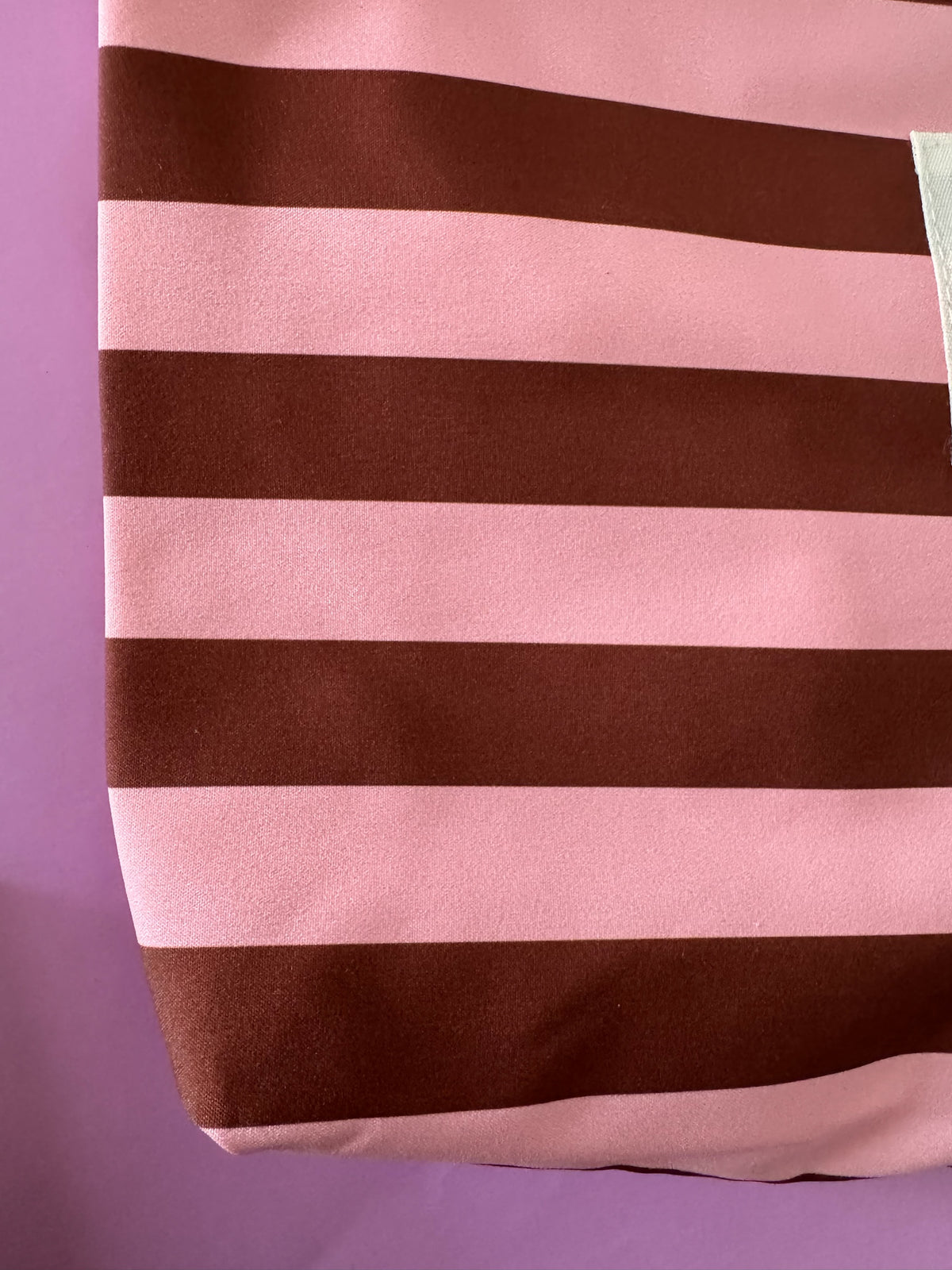 Neceser Brena de tela con diseño de rayas horizontales en color rosa y marrón, ideal para organizar accesorios.