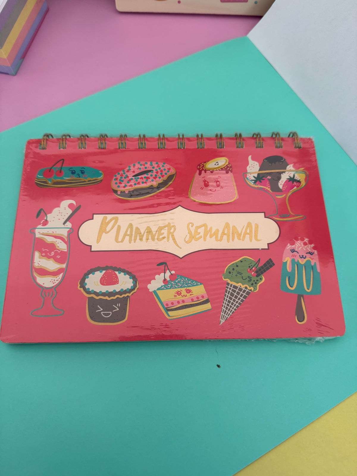 Planner semanal Brena de escritorio con espiral, diseño horizontal rojo con ilustraciones coloridas de postres kawaii.