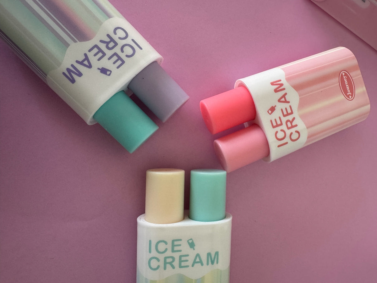 Set de resaltadores Brena con forma de helado, tres unidades de doble punta en tonos pasteles sobre fondo rosa.