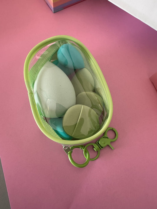 Set de esponjas de maquillaje Brena en tonos verde y azul dentro de un estuche organizador transparente con gancho.