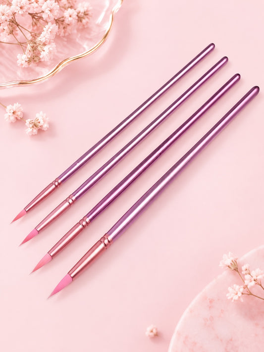 Set de pinceles Brena para uñas con mangos metálicos violetas y cerdas sintéticas rosas sobre fondo rosa pastel.